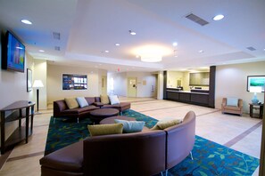 A spacious lobby with a seating area, a reception desk, and a kitchenette.