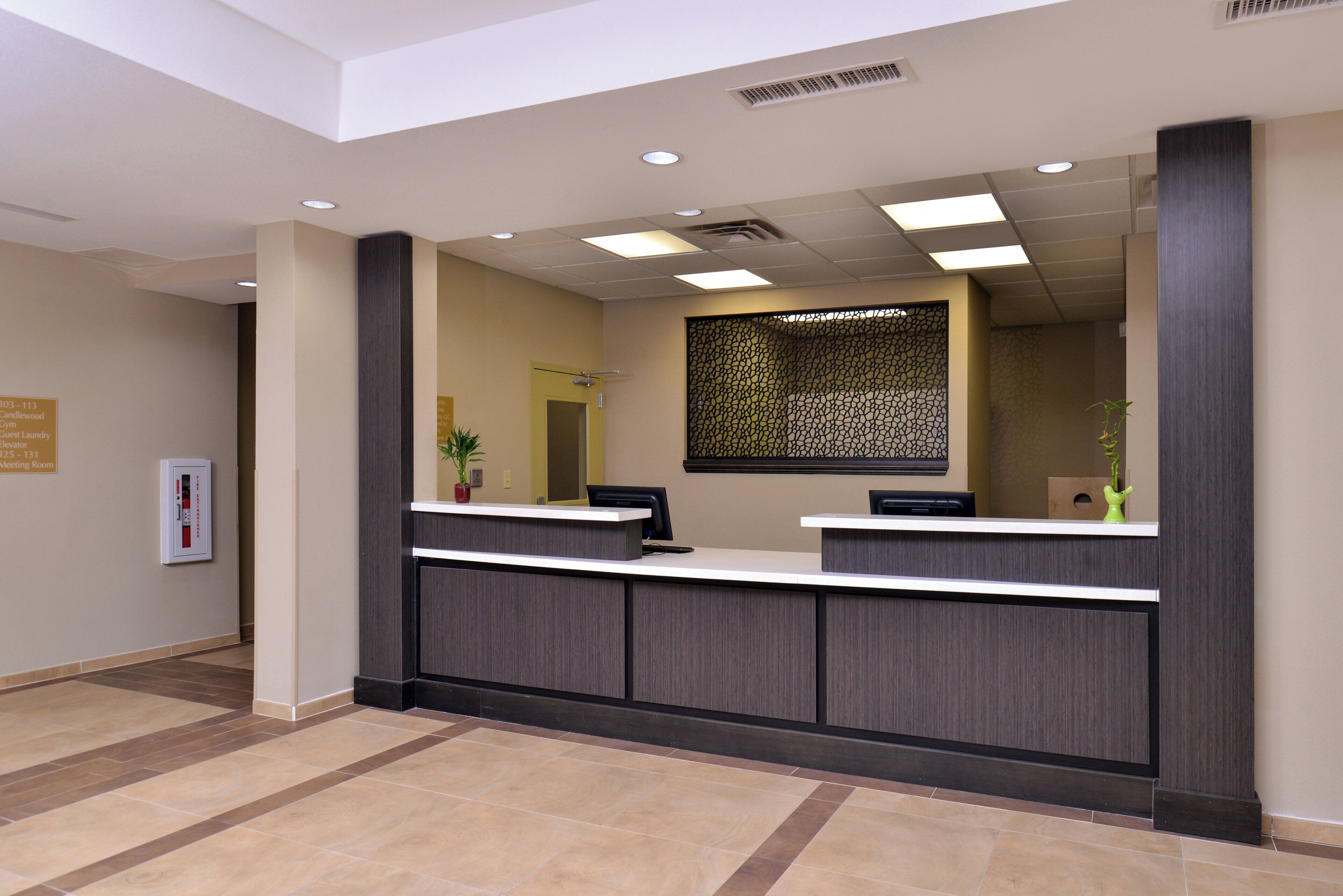 A reception desk with a modern design, a large mirror above it, and a sign indicating the location of the guest laundry and meeting room.