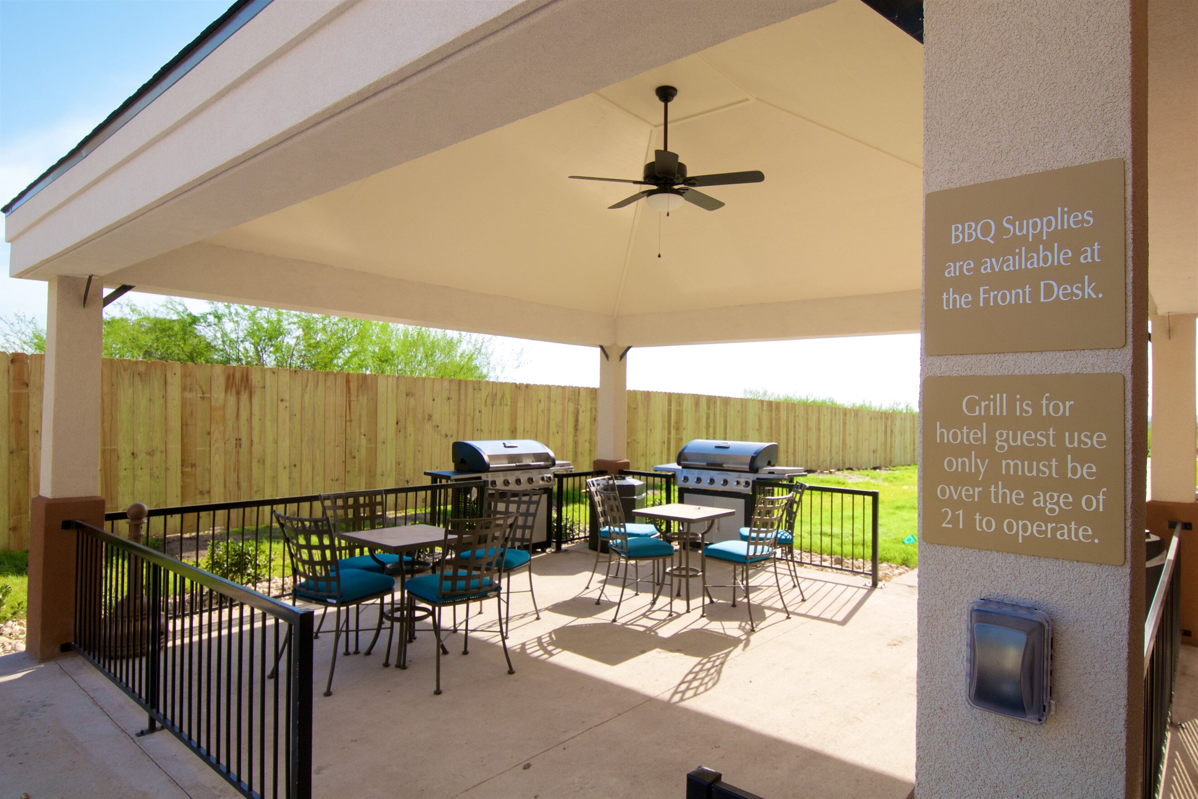 An outdoor patio with a covered seating area, a ceiling fan, and a grill.