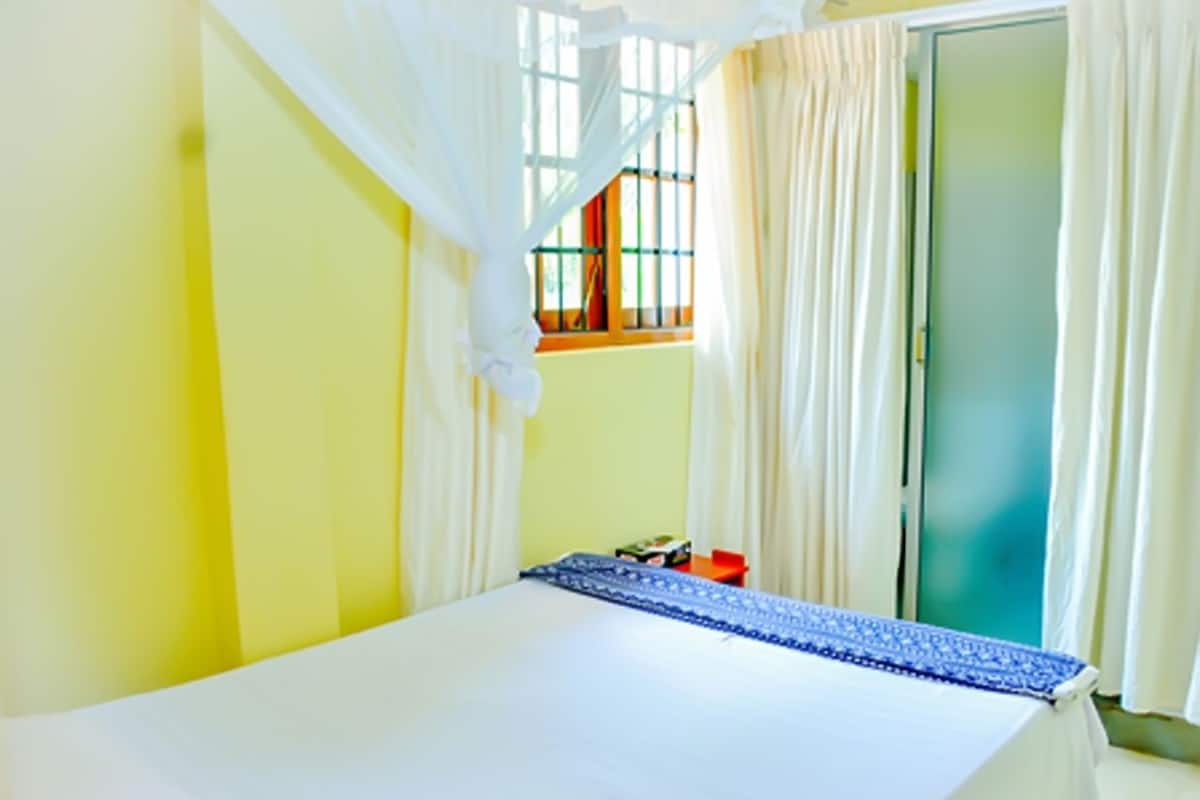 A room with a bed, a window with curtains, and a door.