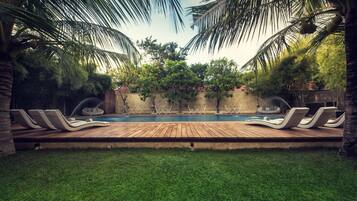 A swimming pool with lounge chairs and a wooden deck.