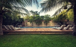 A swimming pool with lounge chairs and a wooden deck.