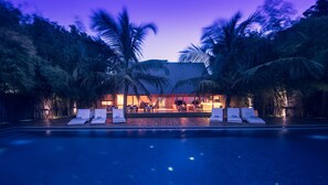 A poolside area with lounge chairs, a bar, and a pool.