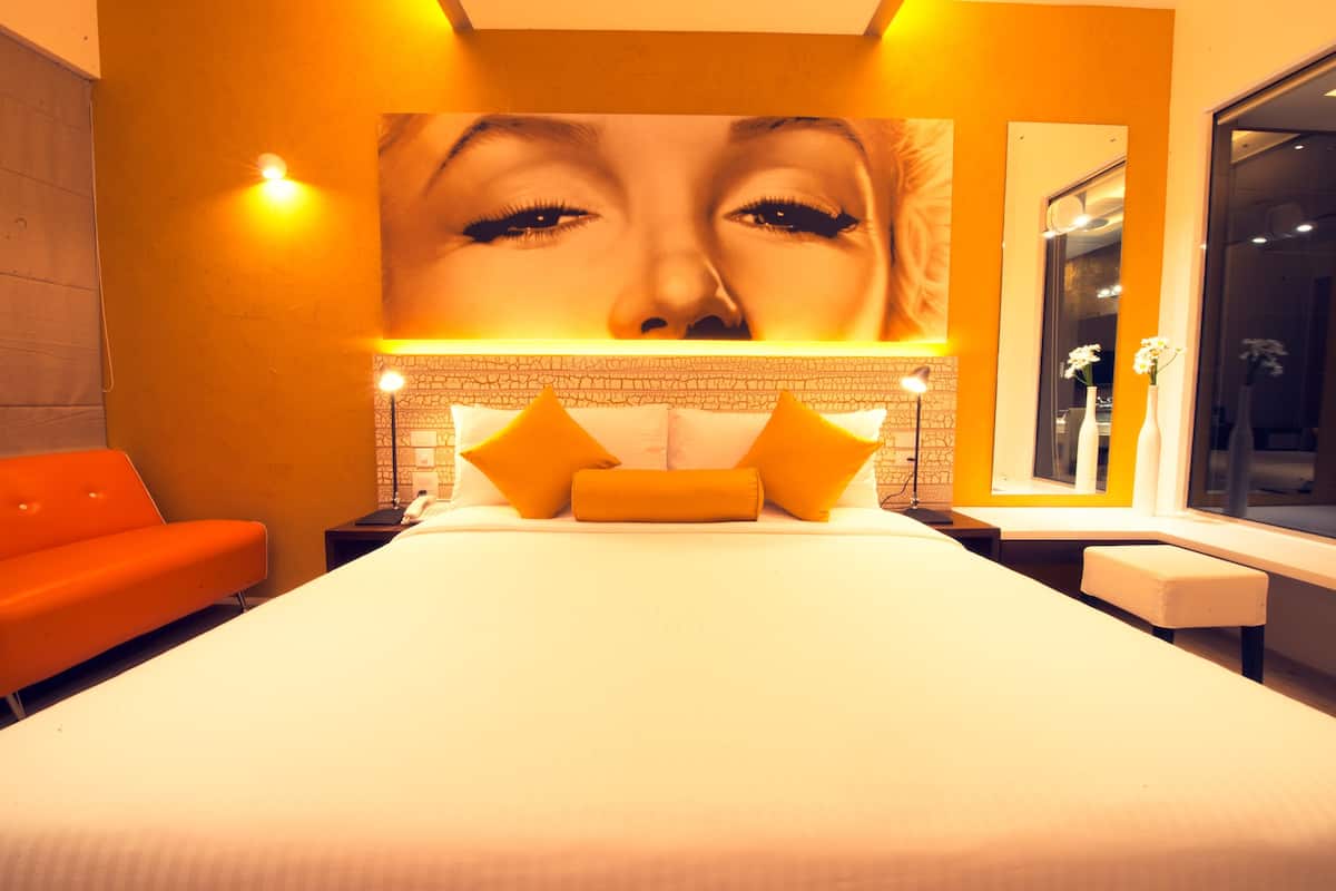 Ein Hotelzimmer mit einem großen Bett, einem Nachttisch, einem Schreibtisch und einem Fenster.