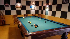 A pool table with balls in a room with checkered walls and wooden furniture. - Danang Backpackers Hostel (Da Nang)