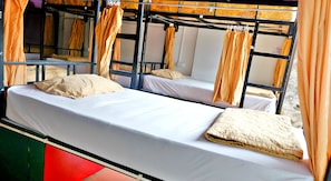 Habitación con literas, dos camas, cada una con colchón blanco y almohadas color crema.