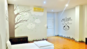A hotel room with a bed, a dresser, and a wall mural. - Danang Backpackers Hostel (Da Nang)
