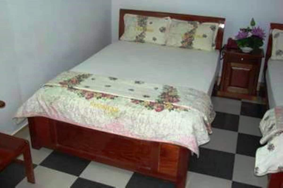 A bedroom with a wooden bed, a nightstand, and a checkered floor.