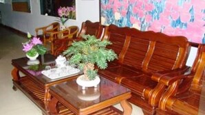 A wooden sofa set with a matching table, a small potted plant, and a decorative tray. - Phu My Hotel (Da Nang)