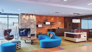 A modern lobby with a stone wall, blue seating, a reception desk, and a large window. - Fairfield Inn & Suites Rawlins (Rawlins)