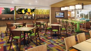 A modern restaurant with wooden tables and chairs, a colorful patterned floor, a counter with a TV, and a view of the outdoors. - Fairfield Inn & Suites Rawlins (Rawlins)