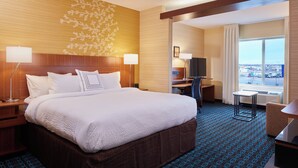 A hotel room with a large bed, a desk, a chair, a TV, and a window with a city view. - Fairfield Inn & Suites Rawlins (Rawlins)