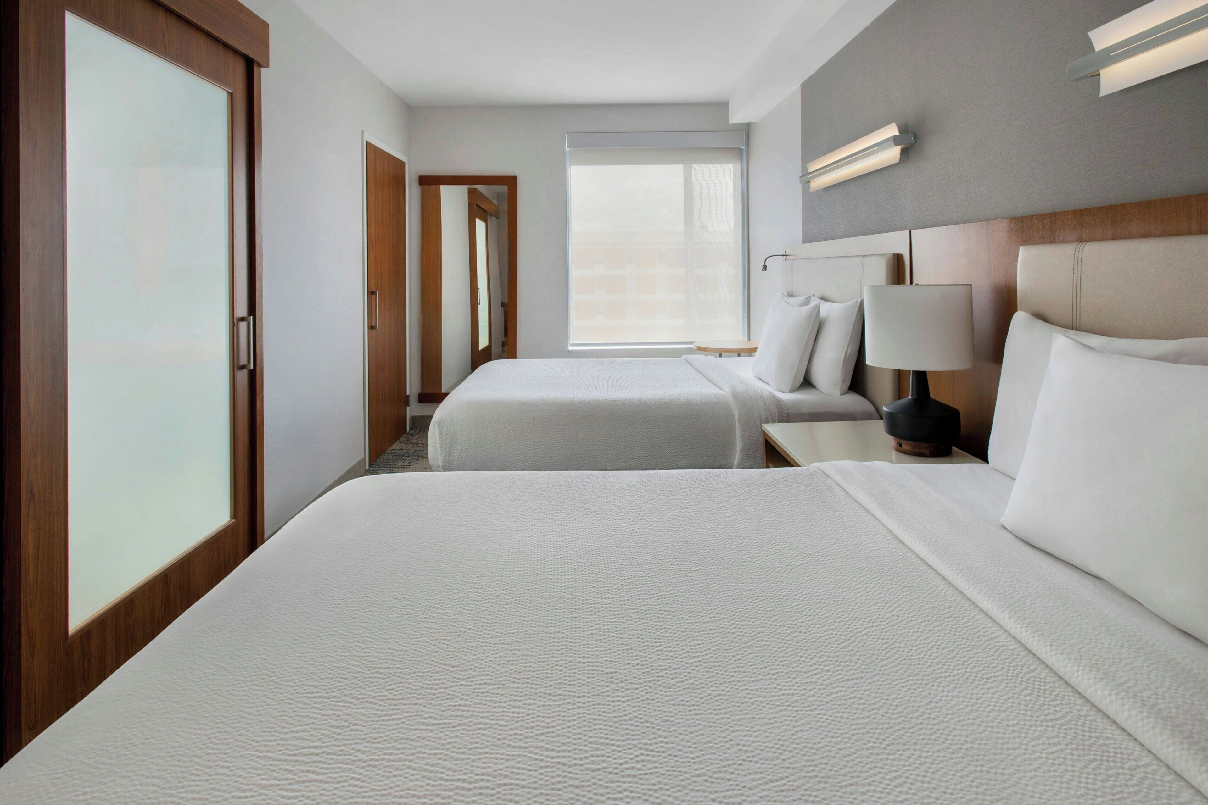 Une chambre d’hôtel avec deux lits, une grande fenêtre et une porte coulissante.