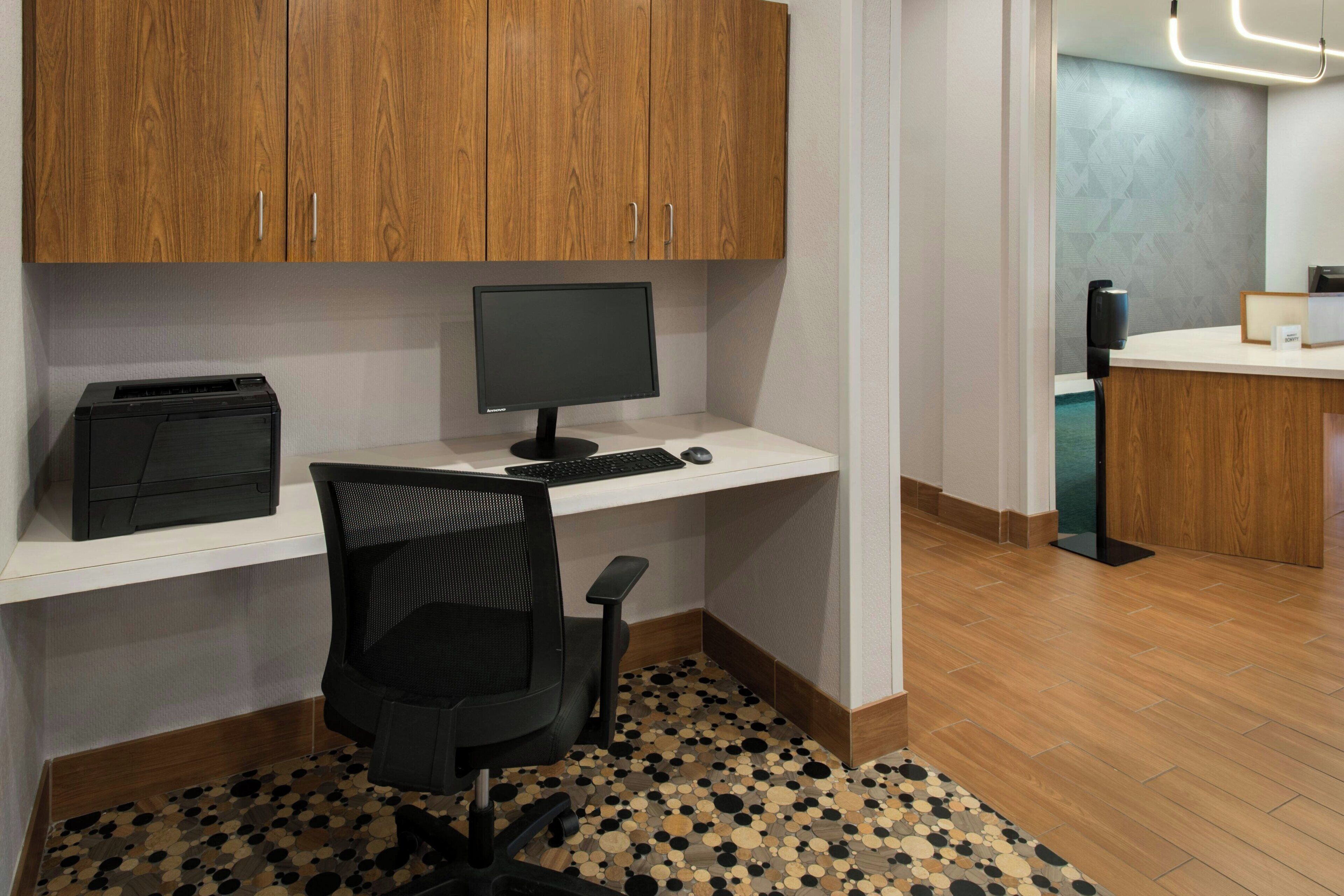 A modern office space with a wooden desk, a computer, a printer, and a chair.