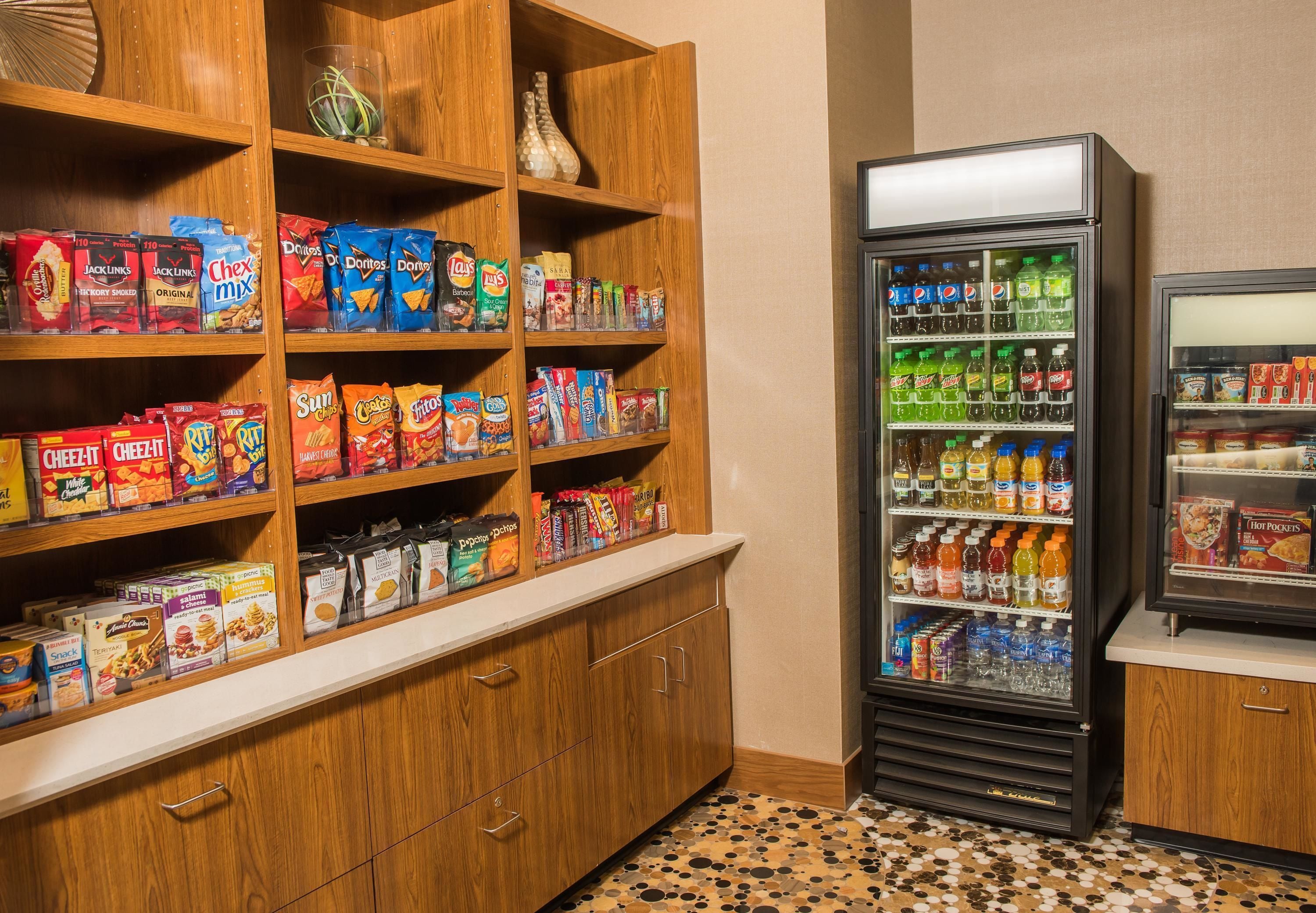 A snack and beverage vending area with various snack options and a refrigerator stocked with drinks.