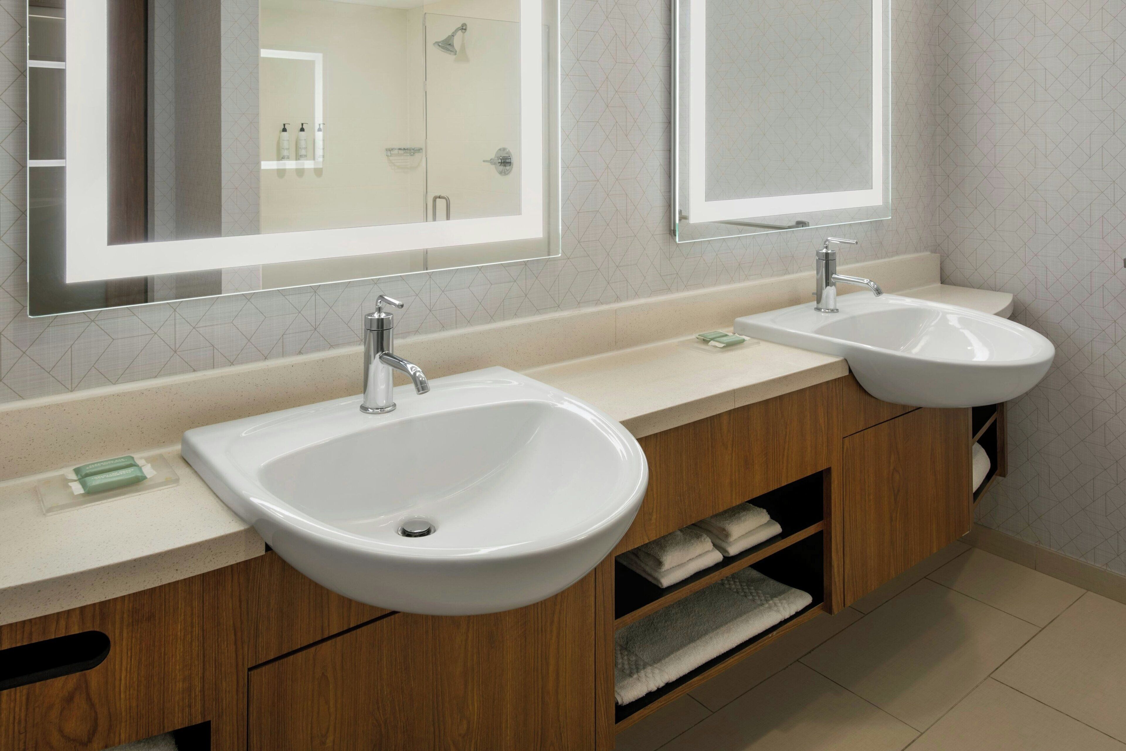 A modern bathroom with two sinks, wooden cabinets, and a large mirror.