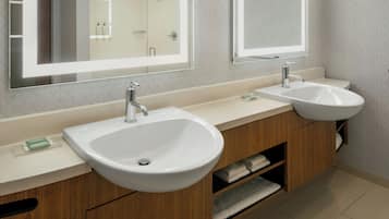 A modern bathroom with two sinks, wooden cabinets, and a large mirror.
