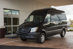 A black Mercedes-Benz Sprinter van parked in front of a building with a glass entrance and a sign indicating 'VFR'. - Springhill Suites Buffalo Airport (Buffalo)