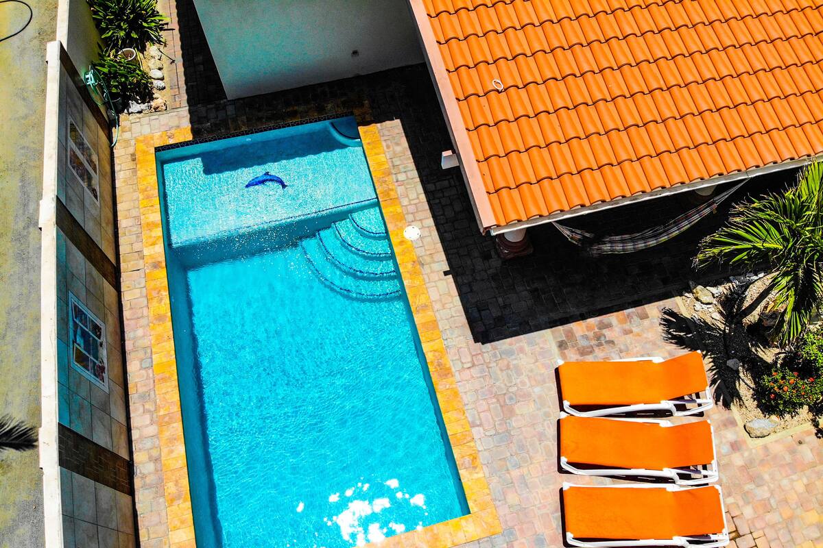 A rectangular swimming pool with a tiled border, surrounded by a brick patio.