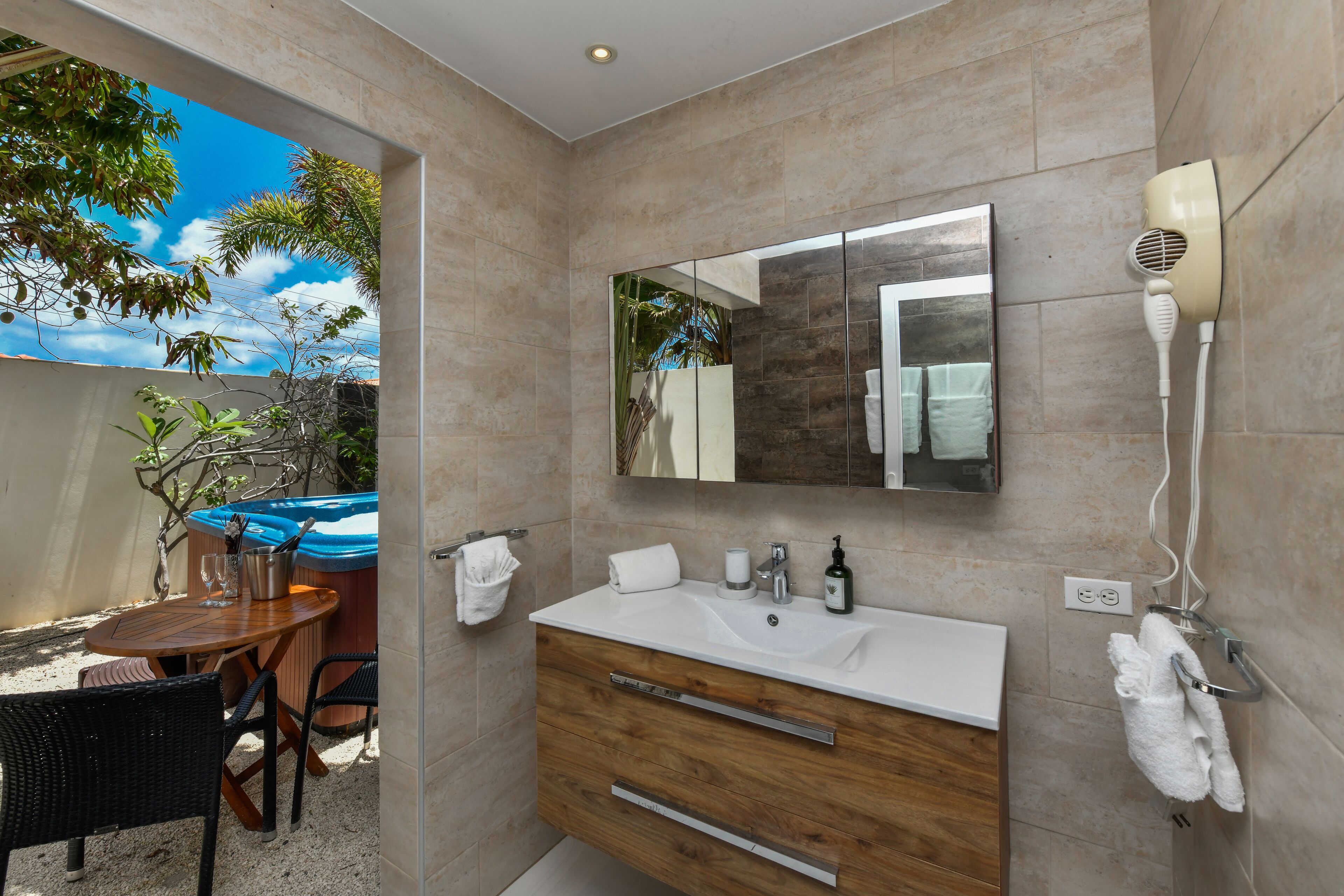 A bathroom with a large mirror, a white sink, and a hairdryer mounted on the wall.
