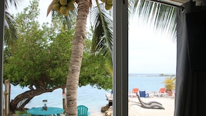 Vista de la playa con una mesa y sillas, palmeras y cielo despejado.