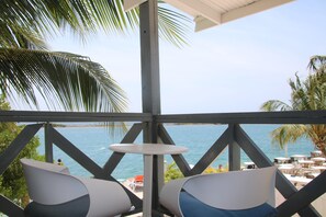 Un espacio de estar al aire libre techado con vistas al mar, con dos sillas y una mesita.