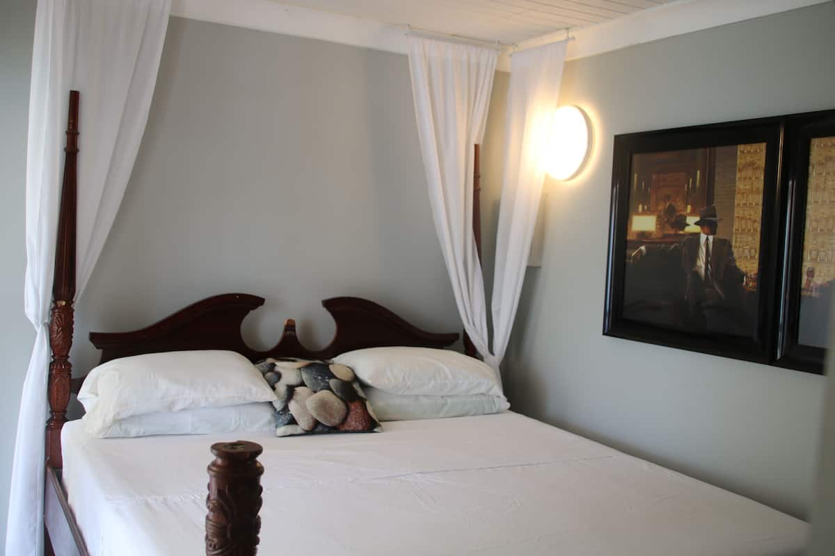 Una cama con ropa blanca, un cabecero de madera y una almohada decorativa.