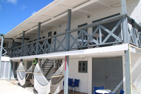A white building with a balcony, blue chairs, and a hammock. - Coral Reef Beach Aruba (Savaneta)