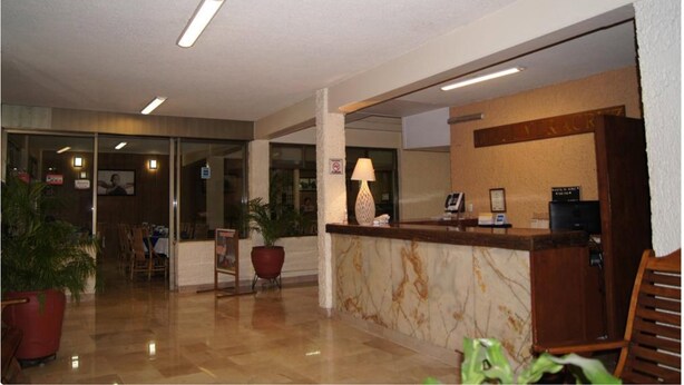 A hotel lobby with a reception desk, a seating area, and a dining space. - Hotel Veracruz (Oaxaca)