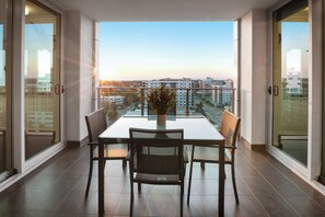 A balcony with a table and chairs, a potted plant, and a city view. - H on Mitchell Apartment Hotel (Darwin)