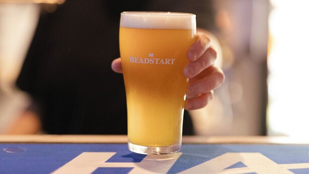 A glass of beer on a bar counter with a logo on the glass. - H on Mitchell Apartment Hotel (Darwin)