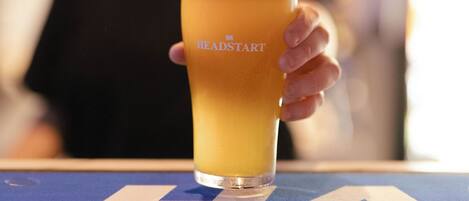 A glass of beer on a bar counter with a logo on the glass.