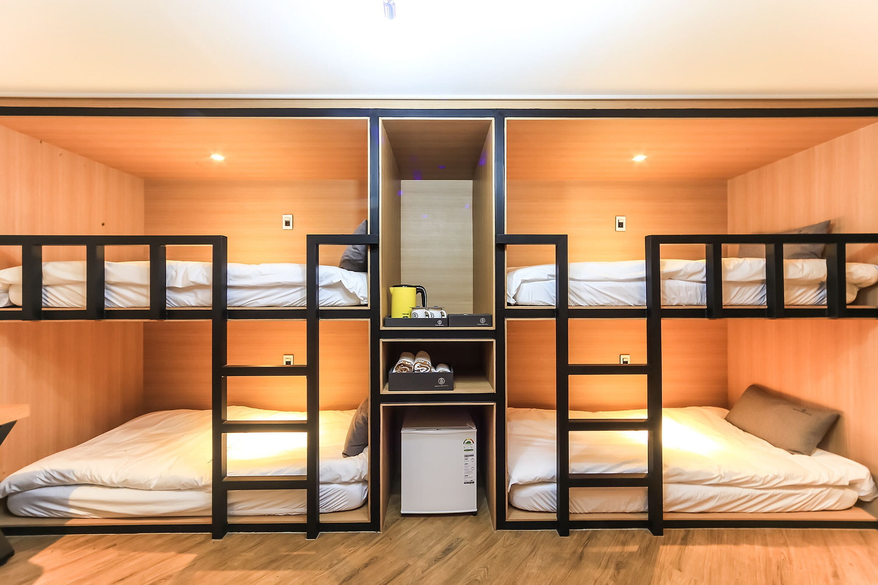 A bunk bed room with wooden walls, a small refrigerator, and a mirror above the beds.