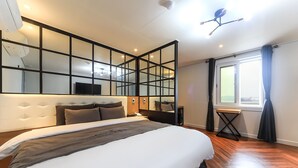 Une chambre d’hôtel moderne équipée d’un grand lit, d’une télévision, d’un bureau et d’une fenêtre avec des rideaux.