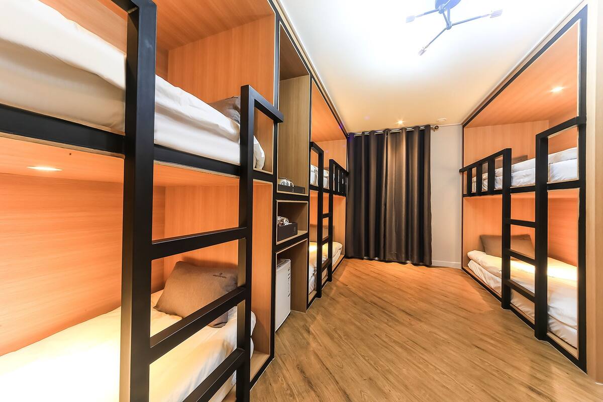 Ein Zimmer mit Etagenbetten, Holzboden und Deckenventilator.