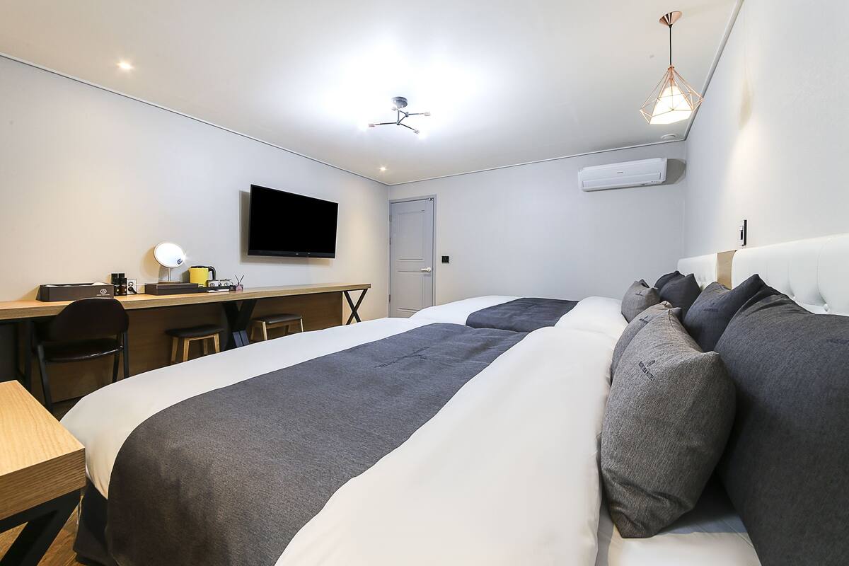 Ein modernes Hotelzimmer mit einem großen Bett, einem Schreibtisch mit Stuhl, einem Flachbildfernseher und einem Deckenventilator.