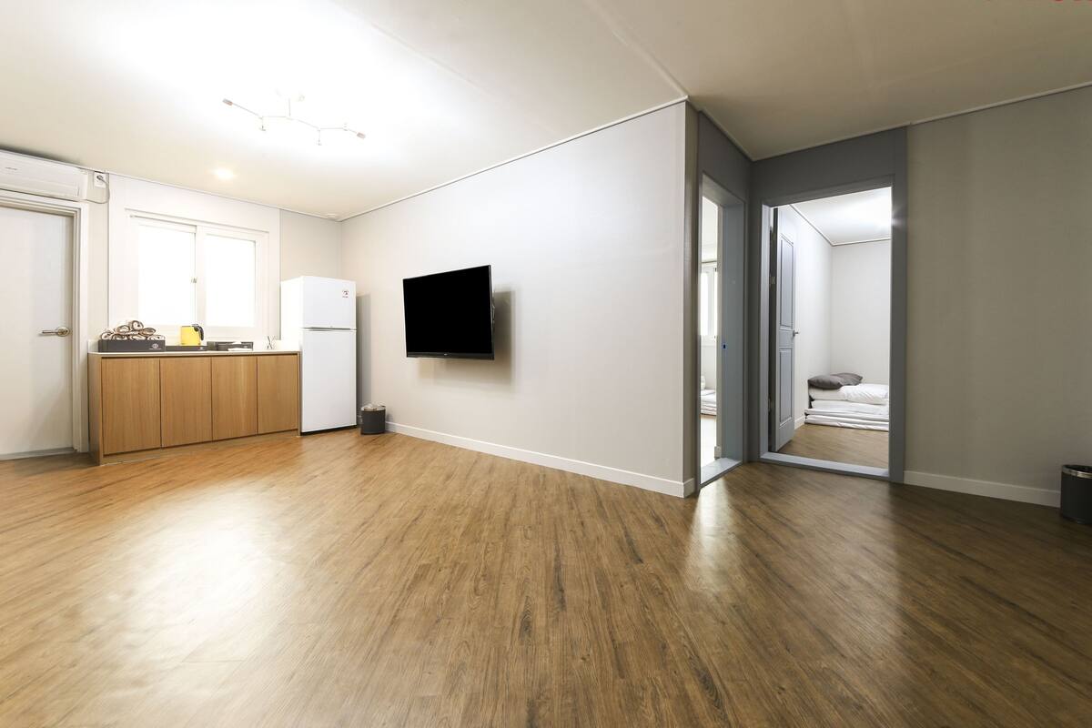 Eine moderne Wohnung mit Küchenbereich, einem wandmontierten Flachbildfernseher und Holzboden.