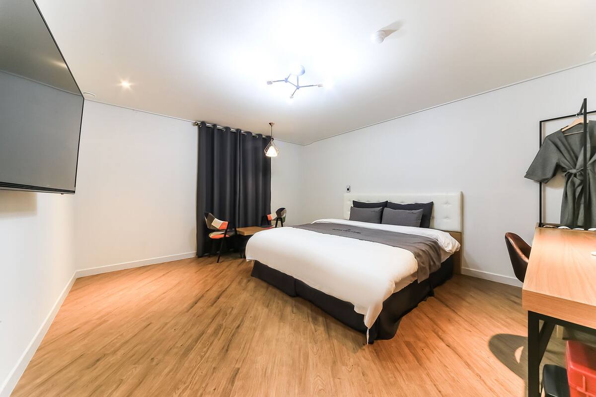 Ein modernes Hotelzimmer mit einem großen Bett, einem Schreibtisch und einem Sessel.