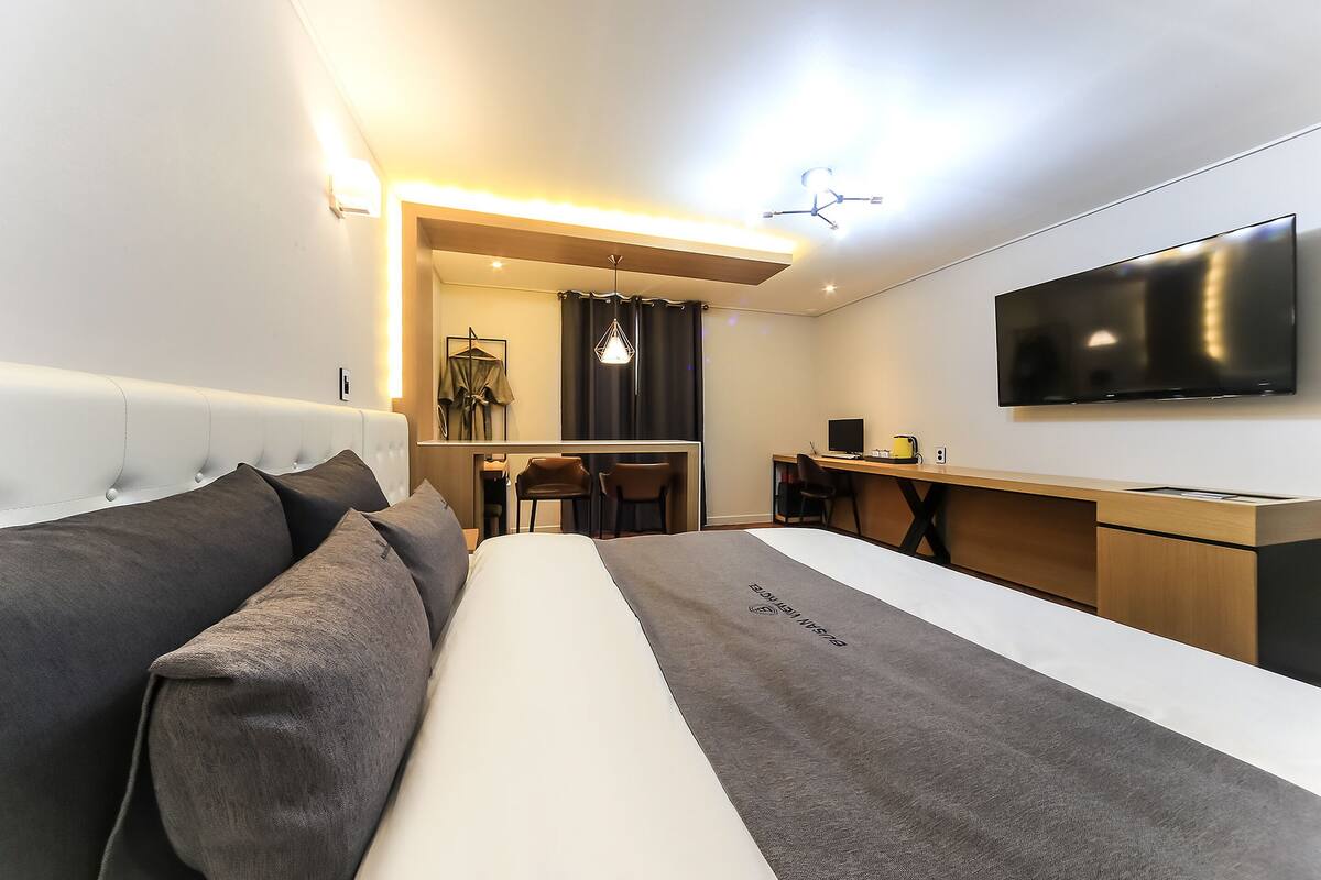 Ein modernes Hotelzimmer mit Bett, Schreibtisch und Fernseher.