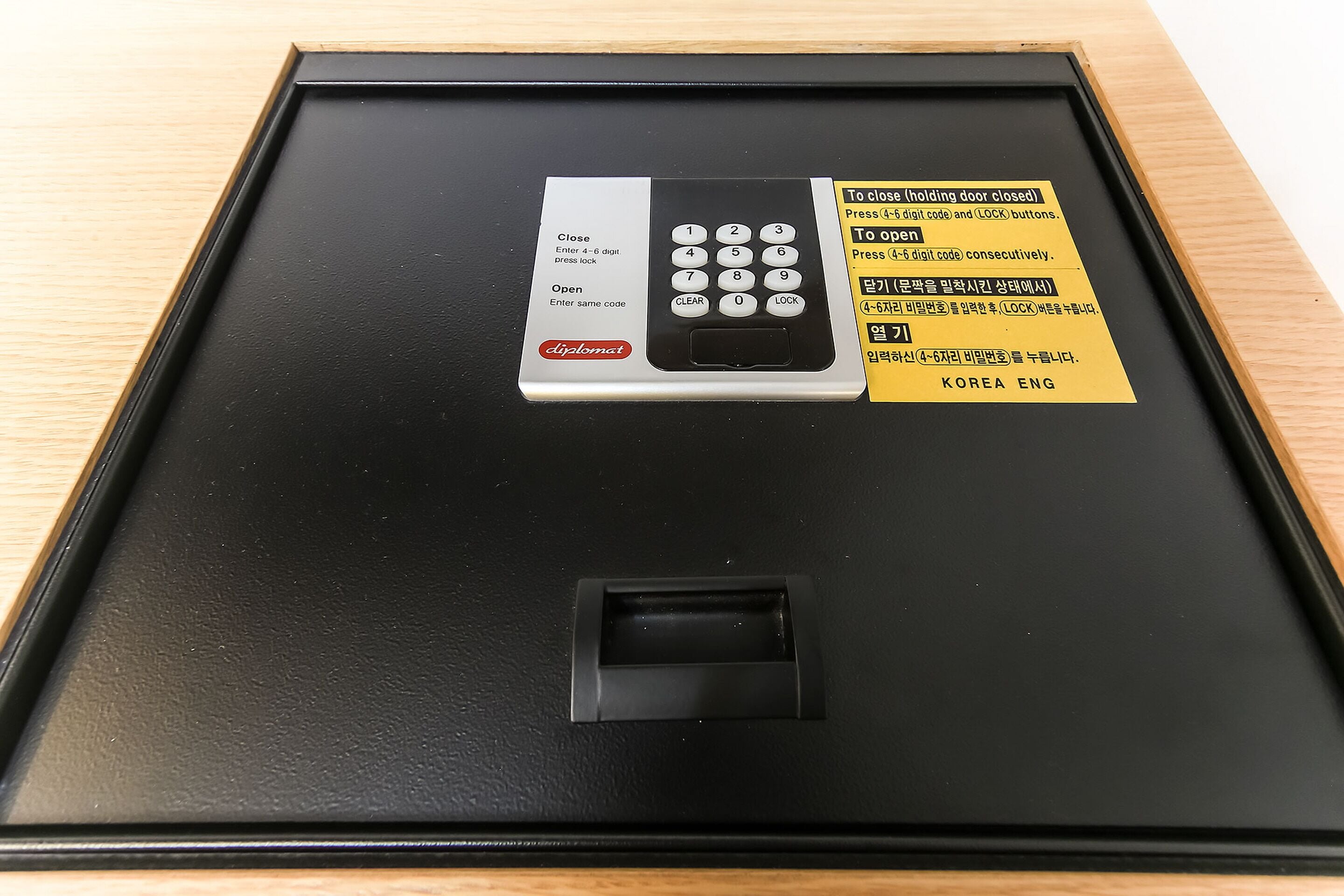 Een zwarte deur met een keypad en een kaartlezer, voorzien van instructies in het Engels en Koreaans.