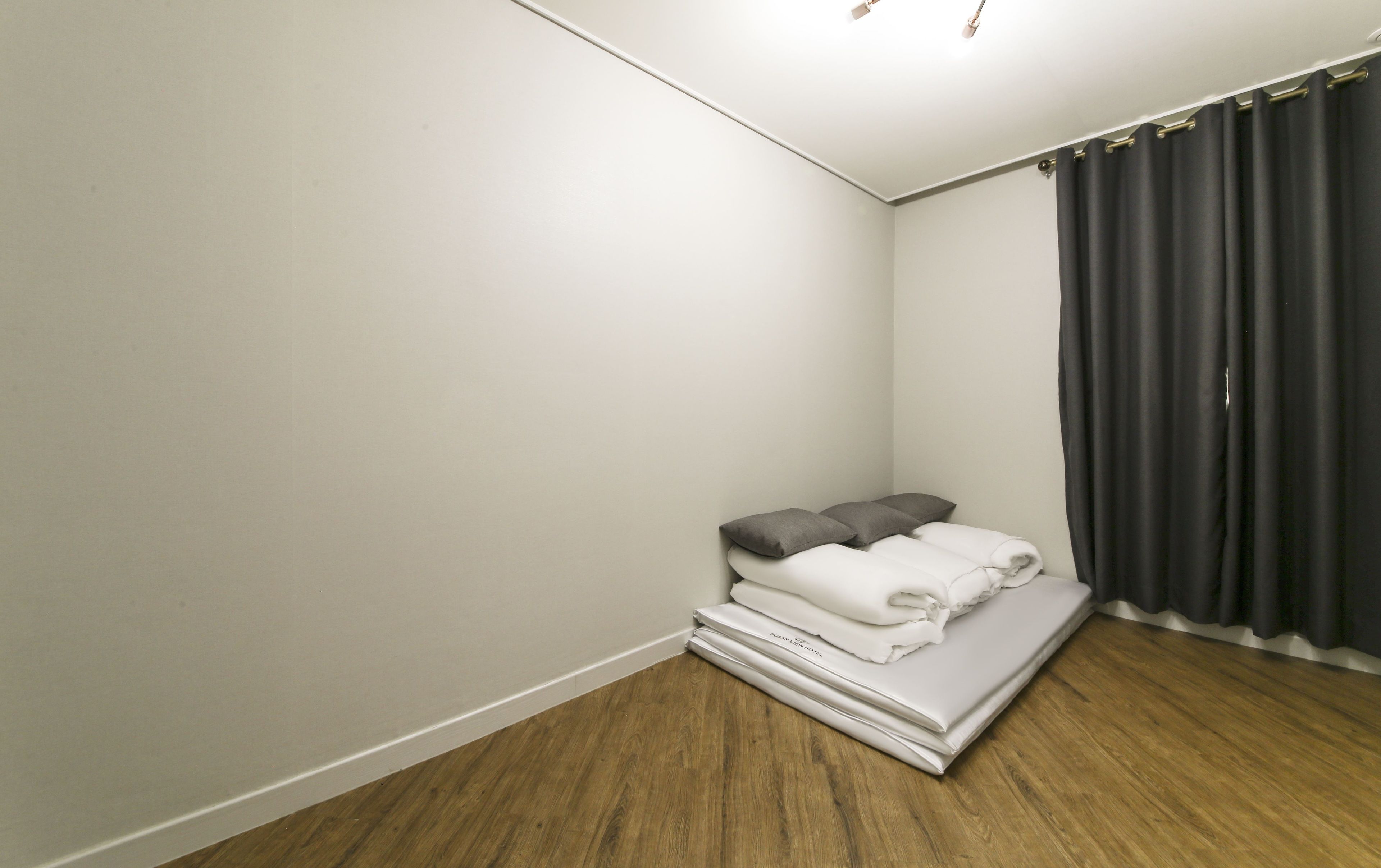 Une petite chambre à coucher, bien rangée, avec un lit, des oreillers et une couverture pliée.