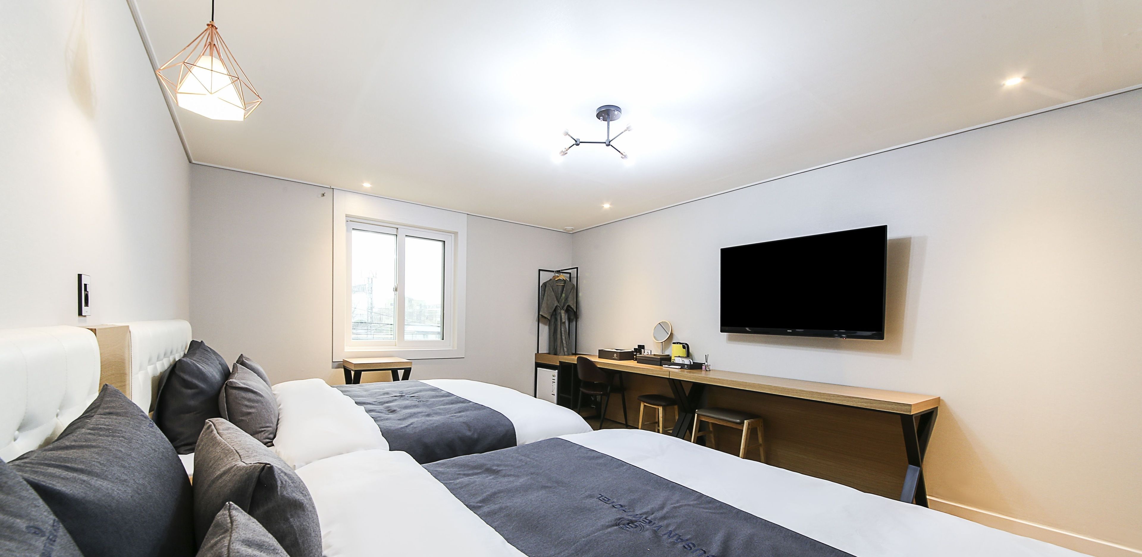 Una habitación de hotel moderna con dos camas, un escritorio, un televisor de pantalla plana y un ventanal grande.