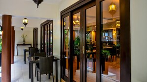 Un couloir agrémenté de meubles en osier et un coin repas avec des tables et des chaises.