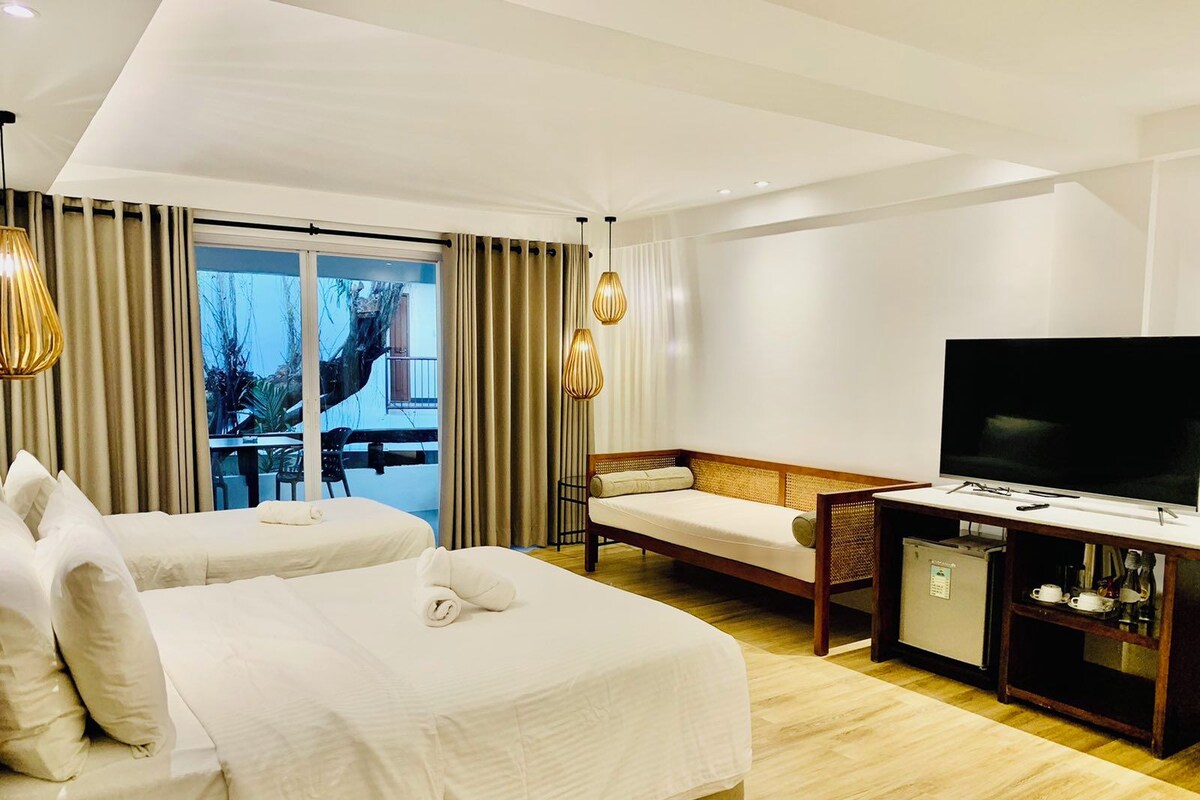 Une chambre d’hôtel avec deux lits, une télévision, un bureau et une vue sur l’extérieur.