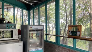 Un área de cocina con refrigerador, microondas y máquina expendedora.