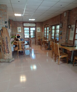 Un restaurante con paredes de ladrillo, mesas y sillas de madera, y grandes ventanales.