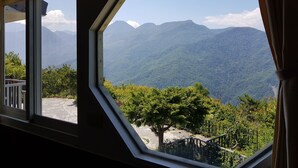 Una habitación con un amplio ventanal de forma octogonal que ofrece vistas a un paisaje montañoso.