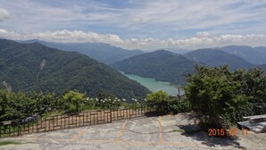 Un paisaje montañoso con cielo despejado, un lago y una zona pavimentada con una cerca.