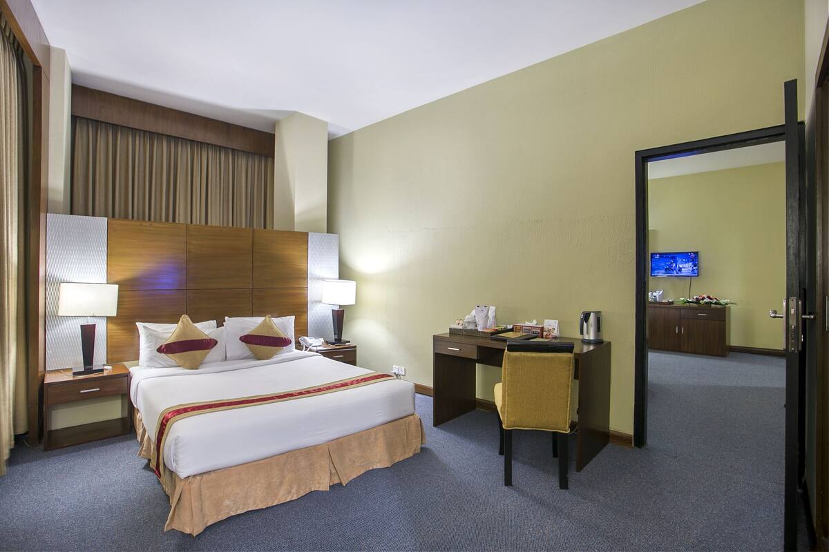 Une chambre d’hôtel comprenant un lit, des tables de chevet, un bureau, une chaise, une télévision et un miroir.