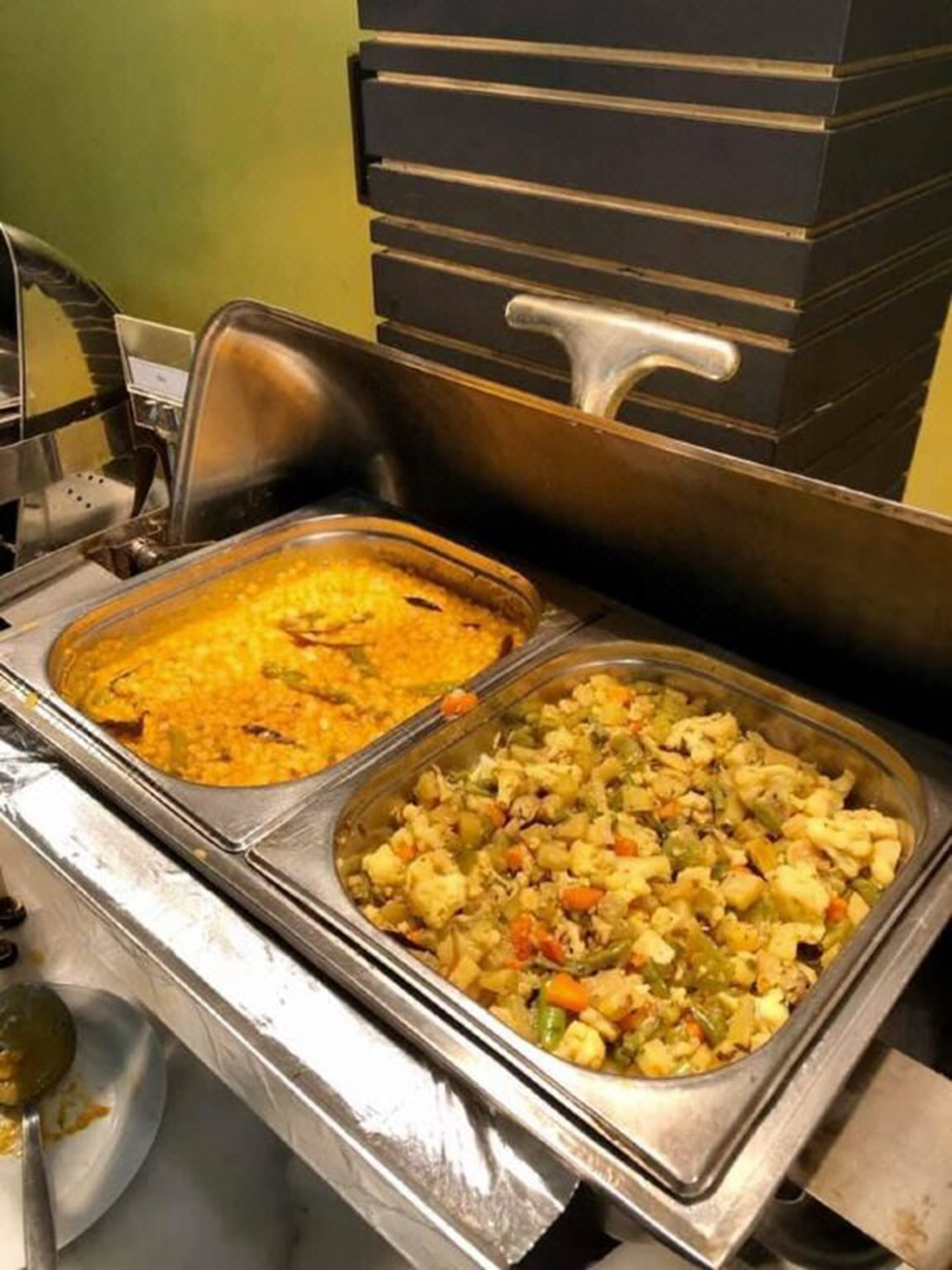 A buffet with two trays of food, one appears to be a rice dish and the other a vegetable stir-fry.